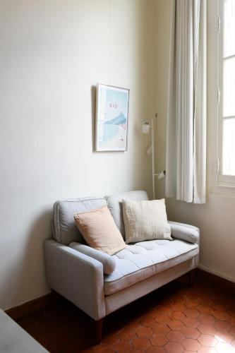a couch sitting in a living room with a window at Cocon provençal dans le centre historique in Aix-en-Provence