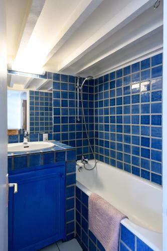 a blue tiled bathroom with a tub and a sink at Cocon provençal dans le centre historique in Aix-en-Provence