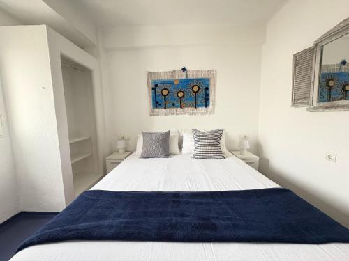 a bedroom with a large white bed with blue blanket at Apartamentos Formentera Copacabana 28 in Es Pujols