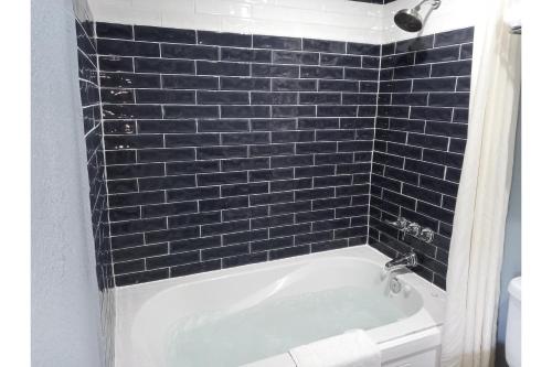 a bath tub in a bathroom with black tiles at Marshall Lodge By OYO Hwy 65 in Marshall