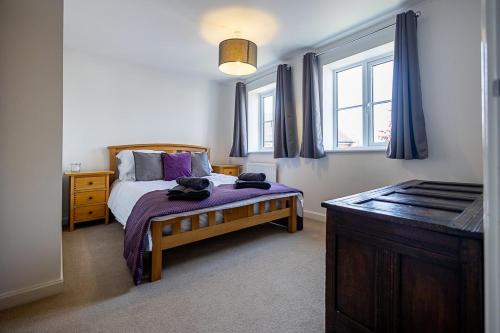 a bedroom with a bed with purple sheets and a window at Spacious 4BD Home with Patio garden, BBQ & Parking in Timsbury