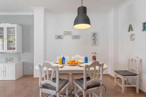 a white kitchen with a table and chairs at Sunset Village in Can Picafort