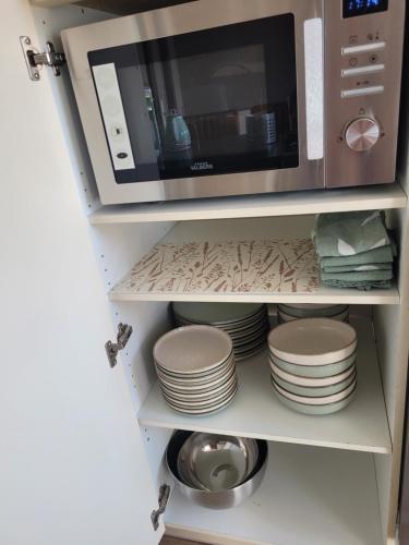 a cupboard with plates and a microwave on it at L'Annexe de Steph in Loulans-Verchamp