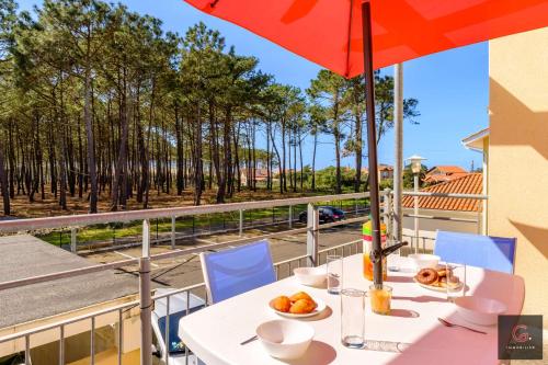 - une table avec un bol de fruits et un parasol sur le balcon dans l'établissement Appartement en Duplex dans résidence avec piscine à Biscarrosse Plage pour 4 personnes, à Biscarrosse