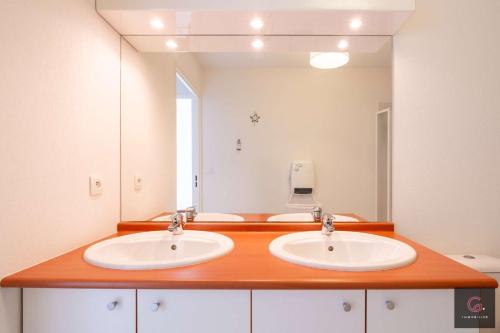 une salle de bain avec deux lavabos et un grand miroir dans l'établissement Appartement en Duplex dans résidence avec piscine à Biscarrosse Plage pour 4 personnes, à Biscarrosse