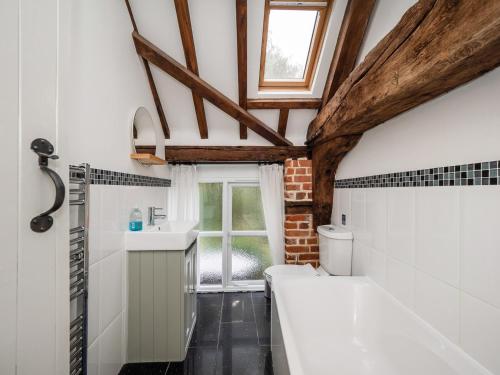 a bathroom with a tub and a sink and a window at Maple Barn: Lux Rural Retreat Near Norfolk Coast in Sutton