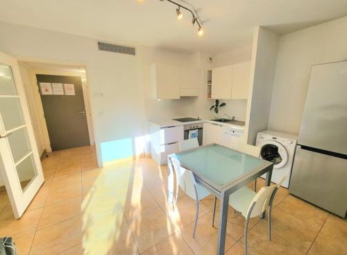 Il comprend une petite cuisine avec une table en verre et un réfrigérateur. dans l'établissement Hambury Palace Menton Garavan Relax and Spa, à Menton