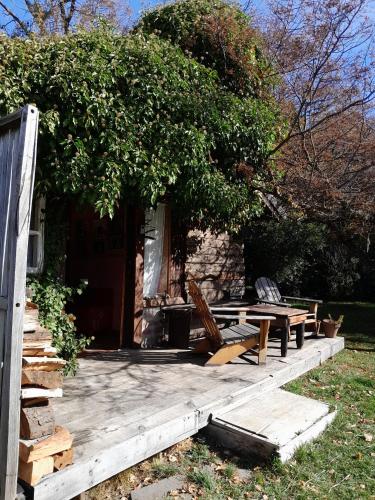 a wooden deck with chairs and a tree at BAJO EL ÑIRE in San Carlos de Bariloche