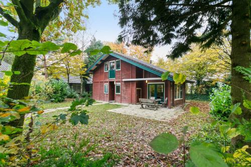 a red house with a bench in a yard at Vacation Home North Limburg in Blitterswijck