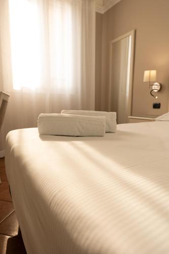 a white bed with two towels on top of it at Hotel Aquila in Castelfranco Emilia