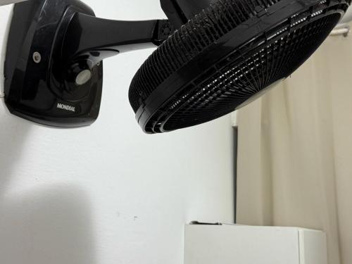 a black hair dryer hanging from a wall at Quarto Leme in Rio de Janeiro