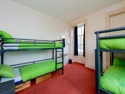 a room with three bunk beds and a red carpet at YHA Coniston Coppermines in Coniston