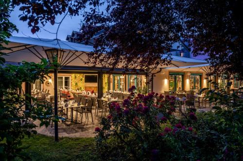 a restaurant with tables and chairs in a garden at Best Western Plus Hotel Erb in Parsdorf