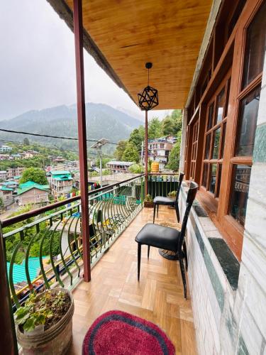 a balcony with a chair and a view at Sharda House in Manāli