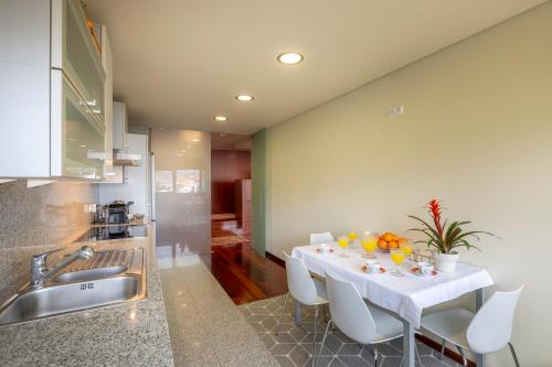 a kitchen with a white table and white chairs at Panoramic City View Apartment - Guimarães in Guimarães
