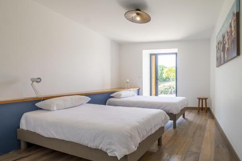 a room with two beds and a window at Le petit Perigord in Fouleix