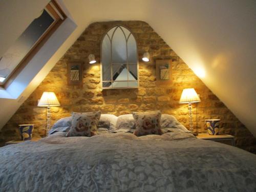 ein Schlafzimmer mit einem großen Bett mit einer Steinwand in der Unterkunft Wonderful Picturesque Countryside Cottage in Bloxham