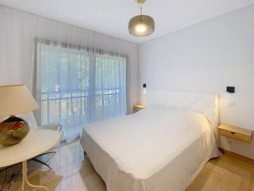 - une chambre blanche avec un lit, une table et une fenêtre dans l'établissement Superbes prestations terrasse piscine mer 350L, à Cannes