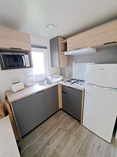 une cuisine avec un réfrigérateur blanc et un évier dans l'établissement Camping Sainte Mère Eglise, à Sainte-Mère-Église
