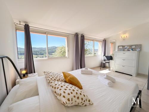 une chambre avec un grand lit blanc et de grandes fenêtres dans l'établissement Maison au Castellet avec piscine, au Castellet