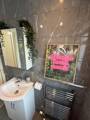 a bathroom with a sink and a welcome to the jungle sign at 1 bed modern apartment walking distance from shopping mall in Golders Green
