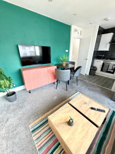 a living room with a table and a tv at 1 bed modern apartment walking distance from shopping mall in Golders Green