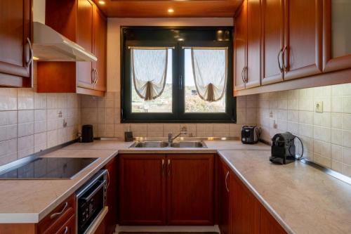 a kitchen with wooden cabinets and a sink and a window at Three Waves Maisonettes Elena in Análipsis