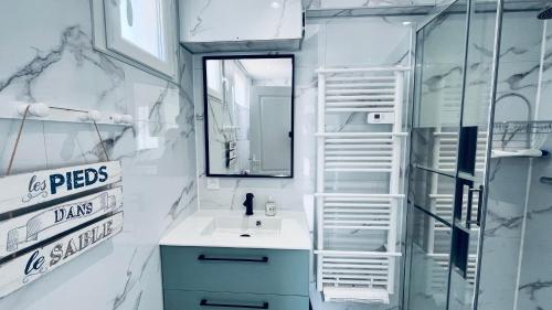 une salle de bain avec un lavabo et un miroir dans l'établissement Maison Hirondelles, piscine mer et forêt, à Saint-Jean-de-Monts