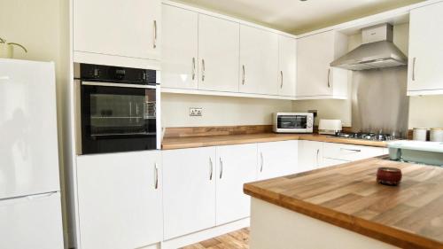 a kitchen with white cabinets and a wooden counter top at 3BD Gem in the Heart of Barnetby Le Wold in Barnetby le Wold