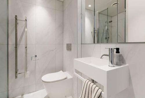 a white bathroom with a toilet and a sink at Urban Oasis - Spacious 3BR Townhouse w Terrace in Wellington