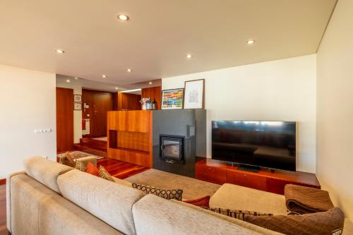 a living room with a couch and a flat screen tv at Panoramic City View Apartment - Guimarães in Guimarães
