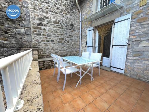 une table et des chaises sur une terrasse avec un mur en briques dans l'établissement Alice Proche Grotte Salamandre & Aven d'Orgnac, à Saint-Jean-de-Maruéjols-et-Avéjan