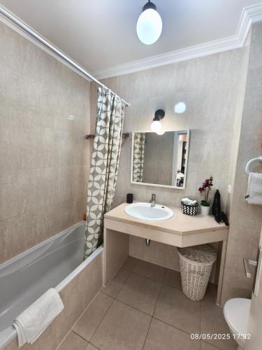 a bathroom with a sink and a tub and a mirror at Apartamento Jeni Residencia Flamingo in Portimão