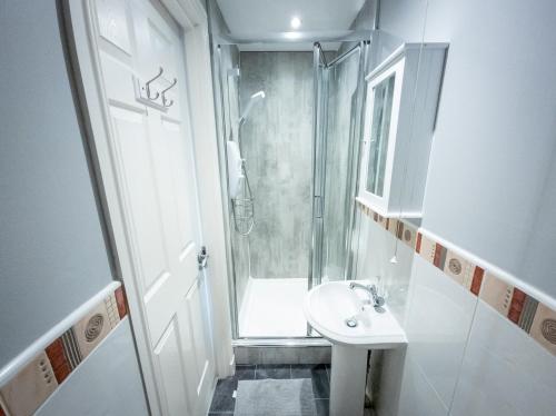 a white bathroom with a shower and a sink at Tranquil 2Bed/2Bath Duplex Falkirk in Falkirk