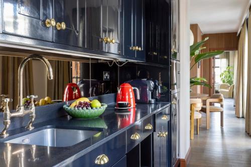a kitchen with black cabinets and a bowl of fruit on the counter at Virgin Hotels London - Shoreditch in London