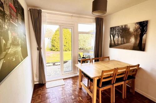 a dining room with a table and chairs and a window at Spacious Family Bungalow with Garden for up to 7 in Epsom