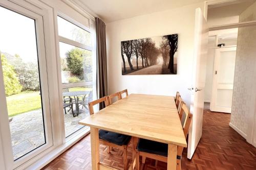 a dining room with a wooden table and a large window at Spacious Family Bungalow with Garden for up to 7 in Epsom