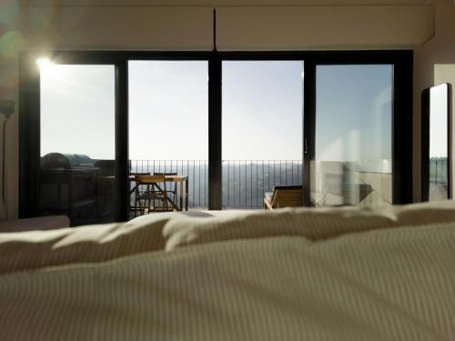 a bedroom with a bed and a room with windows at Il portiot di Langa - Ijan Ospitalità di Borgata in Igliano