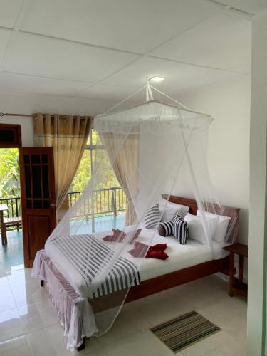 a bedroom with a bed with a mosquito net at Liana Guest House Ella in Ella