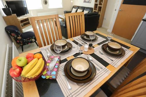 a table with plates and glasses and a bowl of fruit at 3Bed/2Bath Duplex Apartment - Pure Bliss Belfast in Belfast