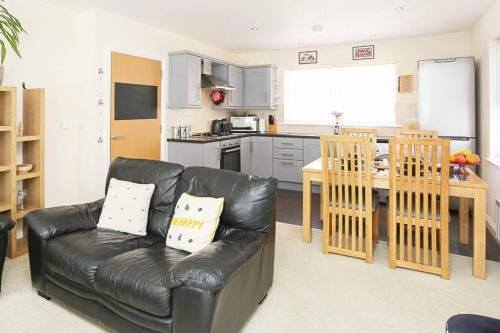 a living room with a leather couch and a kitchen at 3Bed/2Bath Duplex Apartment - Pure Bliss Belfast in Belfast