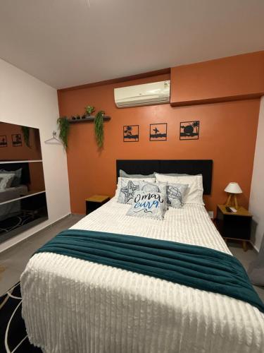 1 dormitorio con 1 cama blanca grande y paredes de color naranja en Studio America Gardens, en Río de Janeiro