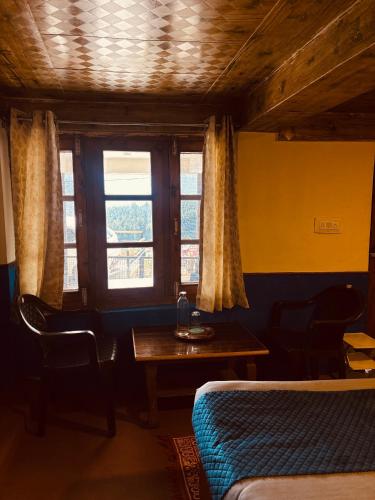 a room with a table and a bed and a window at Sharda House in Manāli