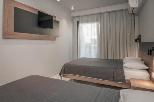 a hotel room with two beds and a television at Elizabeth Queen Luxury Rooms in Paralia Katerinis