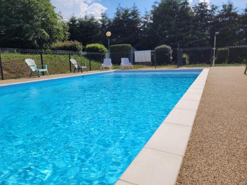 une piscine bleue avec des chaises et une clôture dans l'établissement Chalet Camping Ushuaia Villages du Sabot, à Saint-Maurice-de-Lignon