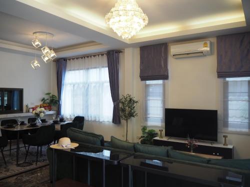 a living room with couches and tables and a television at Private 2-storey house in Chiang Mai By The Orchard in Chiang Mai