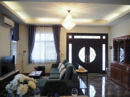 a living room with a green couch and a chandelier at Private 2-storey house in Chiang Mai By The Orchard in Chiang Mai