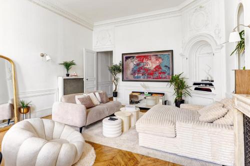 Elle comprend un salon doté d'un mobilier blanc et d'une cheminée. dans l'établissement L'Ecrin Wagram Suite, à Paris