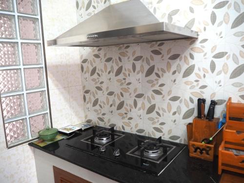 a black stove top in a kitchen with a hood at Private 2-storey house in Chiang Mai By The Orchard in Chiang Mai
