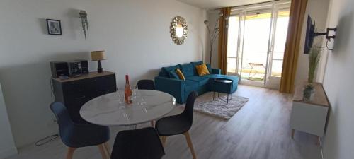 un salon avec une table et un canapé bleu dans l'établissement Appartement vue mer et panoramique, 2 chambres, 3 lits, à Nice